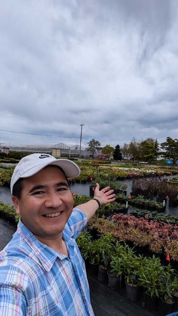 Reza standing in a nursery with rows of healthy plants.